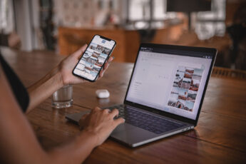 Woman edits social media content on phone and laptop at a cafe